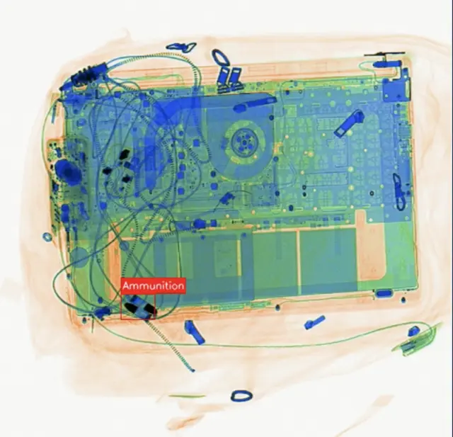 AI X-ray detection flagging ammunition beside a laptop